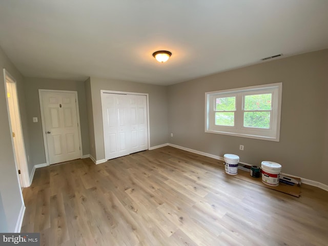 unfurnished bedroom with a closet, baseboards, visible vents, and light wood-type flooring