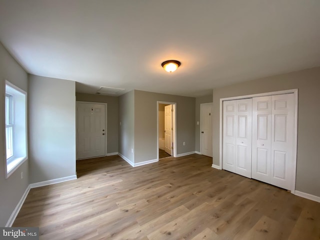 unfurnished bedroom featuring connected bathroom, baseboards, wood finished floors, and a closet