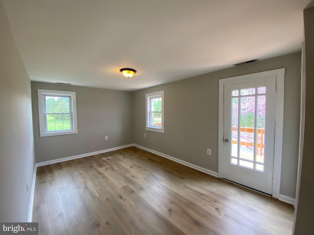 empty room with baseboards, visible vents, and wood finished floors