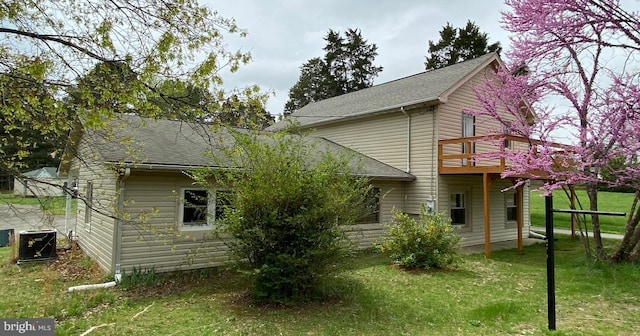 back of house featuring a lawn, a wooden deck, a shingled roof, and central AC