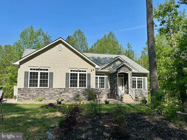 view of front facade featuring a front lawn and stone siding