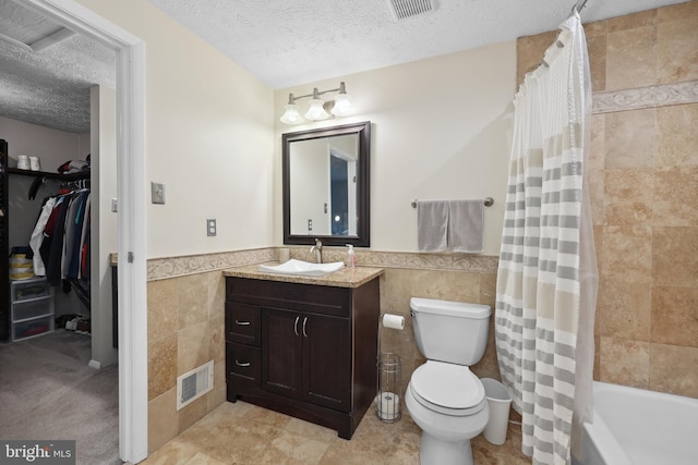8140 Willowdale Ct, Springfield, VA 22153 - full bathroom featuring tile walls, a wainscoted wall, a textured ceiling, toilet, and vanity