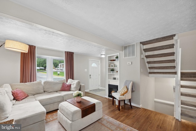 8140 Willowdale Ct, Springfield, VA 22153 - living area featuring a textured ceiling, wood finished floors, stairs, a glass covered fireplace, and baseboards