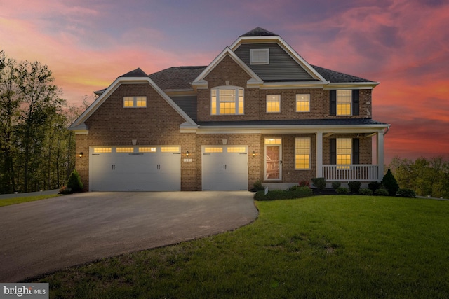 view of front of home with covered porch, driveway, a garage, brick siding, and a yard