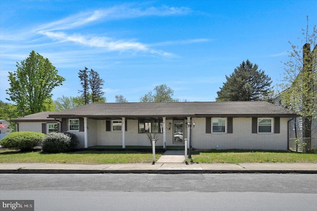 ranch-style home with brick siding, covered porch, and a front yard