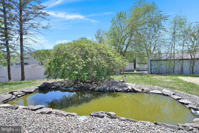 dock area with fence, a garden pond, and a lawn