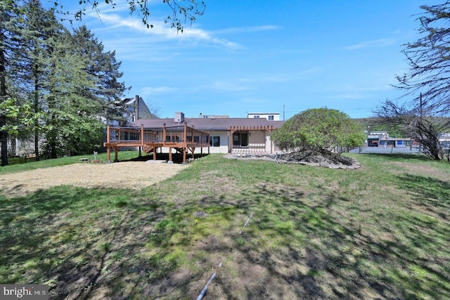 rear view of house featuring a lawn and a wooden deck