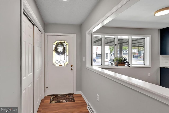 doorway to outside featuring baseboards and wood finished floors