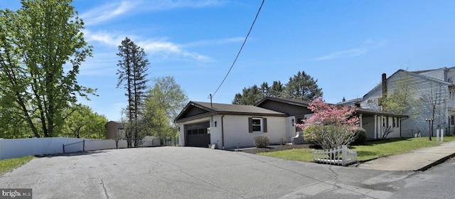 ranch-style home with aphalt driveway, fence, and a garage