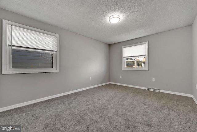 unfurnished room featuring baseboards, carpet flooring, a textured ceiling, and visible vents