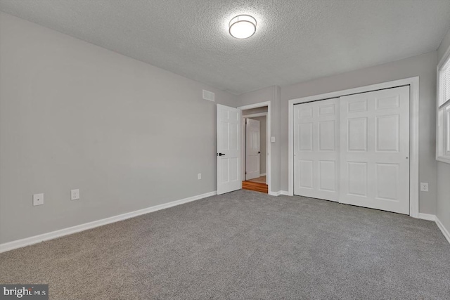 unfurnished bedroom with carpet floors, a textured ceiling, baseboards, and a closet