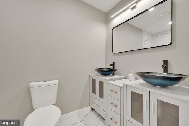 bathroom with toilet, baseboards, marble finish floor, and vanity