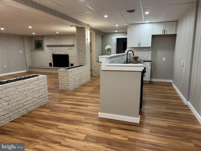 kitchen with white cabinets, baseboards, a brick fireplace, and a sink
