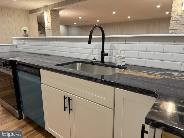 kitchen featuring a sink, light wood finished floors, dishwashing machine, and white cabinetry