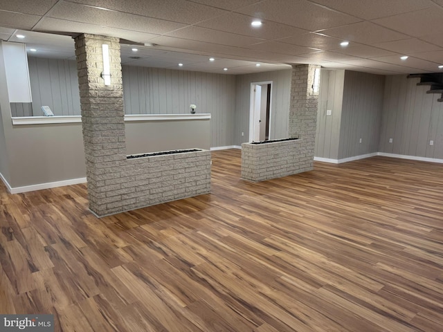 interior space featuring baseboards, a paneled ceiling, and wood finished floors