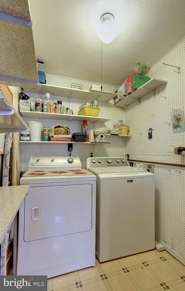 washroom with washing machine and clothes dryer, laundry area, a textured ceiling, wallpapered walls, and light floors