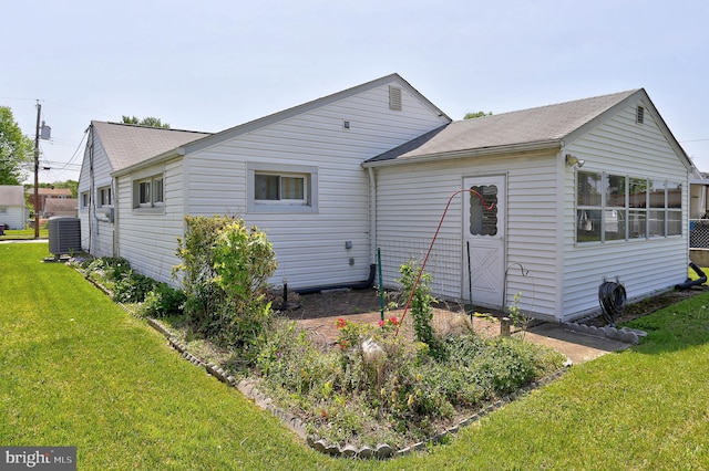 back of house featuring a shingled roof, a yard, and cooling unit