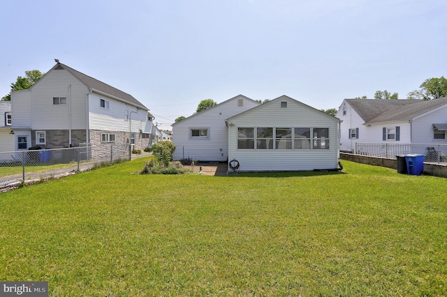 rear view of property featuring a sunroom, fence, and a yard