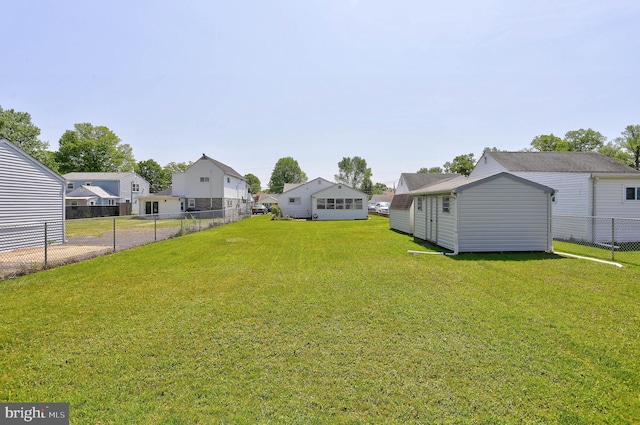 view of yard featuring a storage shed, fence, a residential view, and an outdoor structure