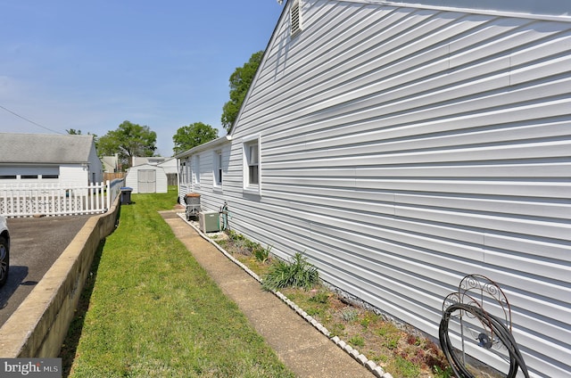 view of property exterior featuring a storage shed, a lawn, fence, and an outdoor structure