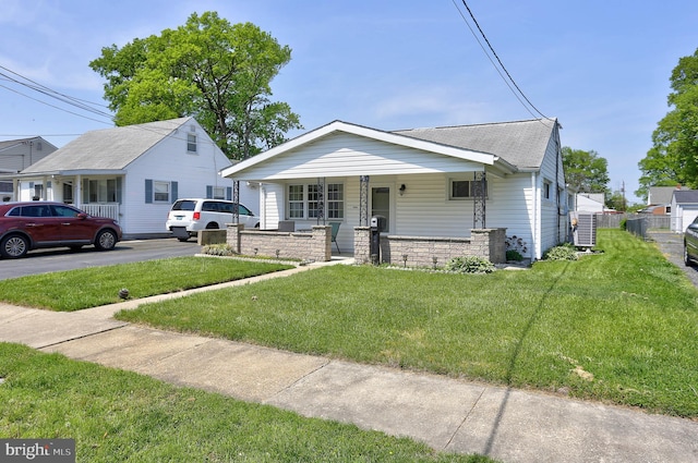 bungalow featuring fence, covered porch, a shingled roof, and a front yard