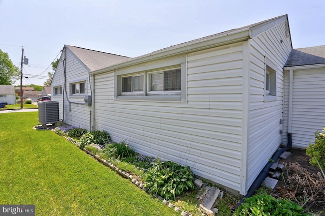 view of home's exterior featuring a lawn, central AC, and roof with shingles