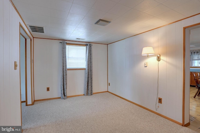 carpeted spare room with visible vents and ornamental molding