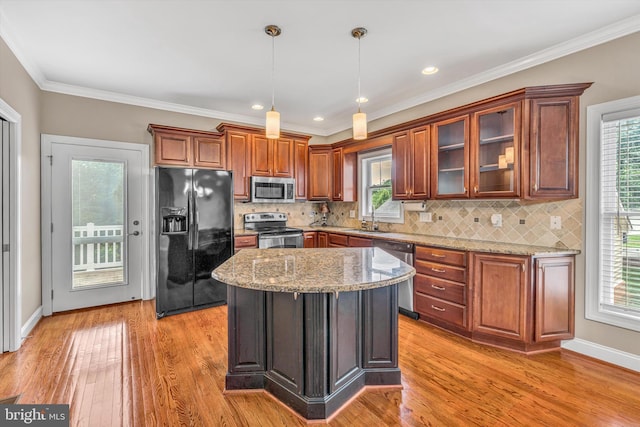 kitchen with stainless steel appliances, light stone countertops, hanging light fixtures, and light wood-style floors