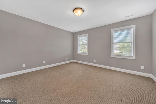 carpeted spare room featuring baseboards and visible vents