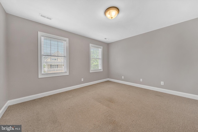 carpeted spare room featuring visible vents and baseboards