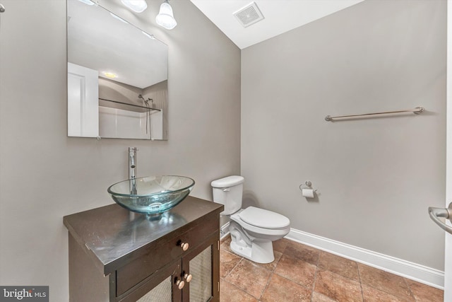 bathroom featuring stone finish floor, visible vents, baseboards, vanity, and toilet