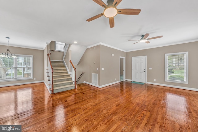 unfurnished living room with baseboards, visible vents, a healthy amount of sunlight, and ceiling fan with notable chandelier