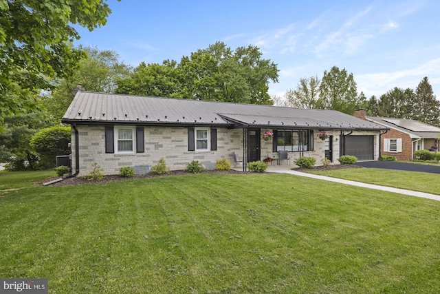 ranch-style home with a chimney, driveway, metal roof, a garage, and a front lawn