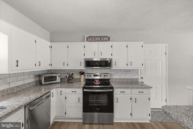 1004 Marietta Ave, Hanover, PA 17331 - kitchen with stainless steel appliances, light wood-style flooring, white cabinetry, and tasteful backsplash