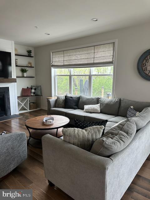 living room with recessed lighting, dark wood-style flooring, and a large fireplace