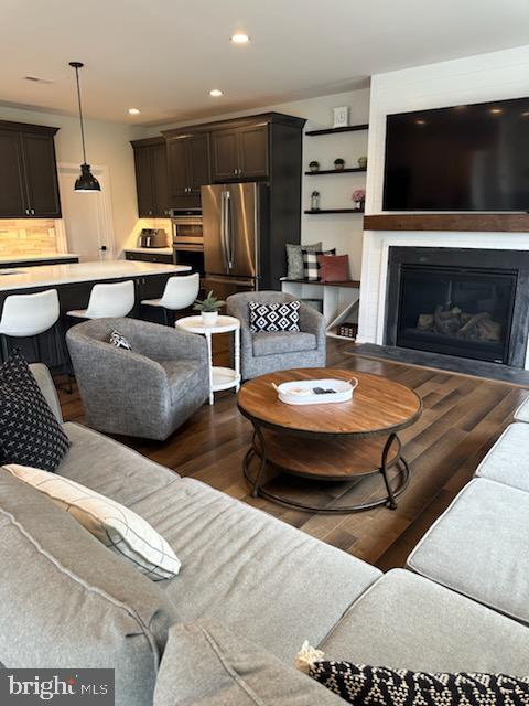 living room with recessed lighting, wood finished floors, and a fireplace