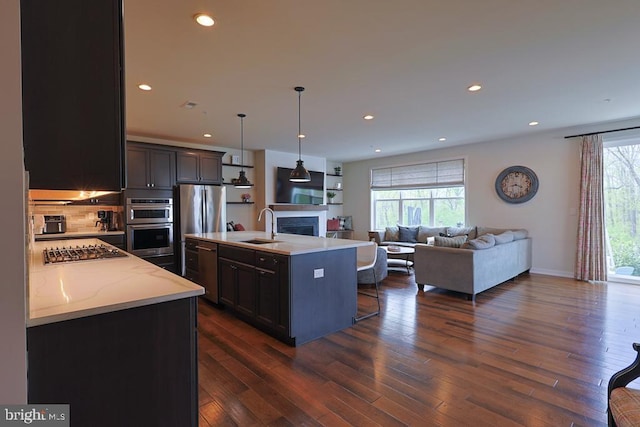 kitchen with open floor plan, appliances with stainless steel finishes, a healthy amount of sunlight, and a sink
