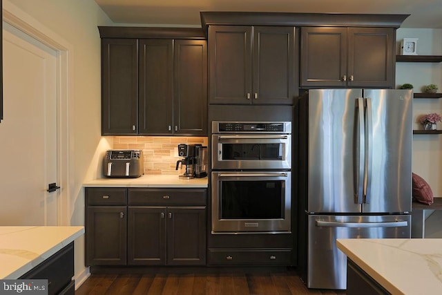 kitchen with light stone countertops, open shelves, appliances with stainless steel finishes, tasteful backsplash, and dark wood-style floors