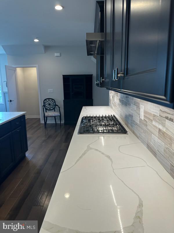 kitchen with light stone countertops, stainless steel gas cooktop, wall chimney exhaust hood, recessed lighting, and tasteful backsplash