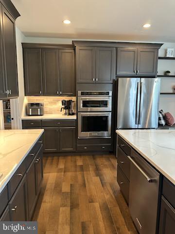 kitchen featuring recessed lighting, light stone counters, dark wood-style floors, and stainless steel appliances