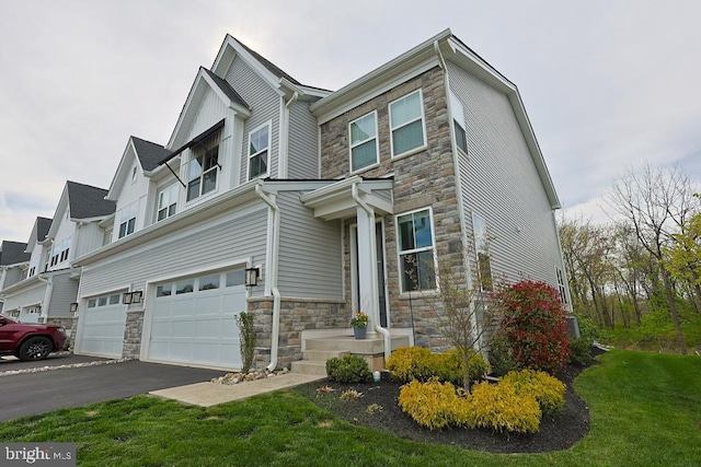 view of front of home featuring a garage, a front lawn, driveway, and stone siding
