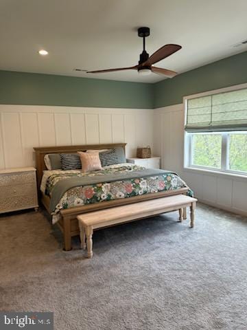 carpeted bedroom with a ceiling fan and a decorative wall