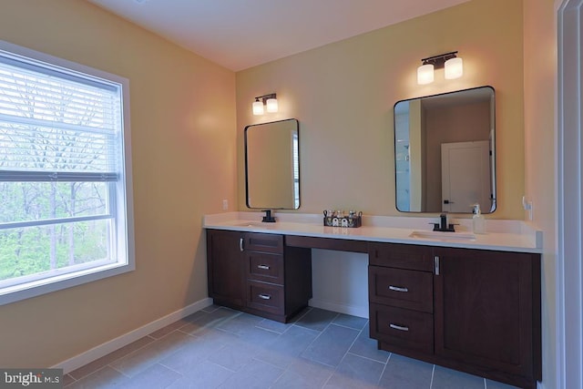 bathroom featuring double vanity, baseboards, a sink, and tile patterned floors