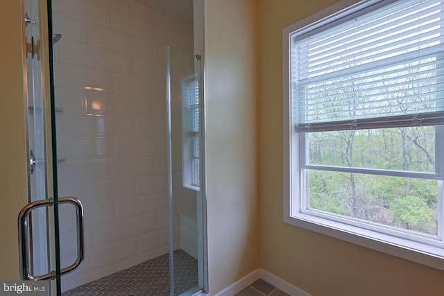 full bath with tile patterned floors, plenty of natural light, baseboards, and a stall shower