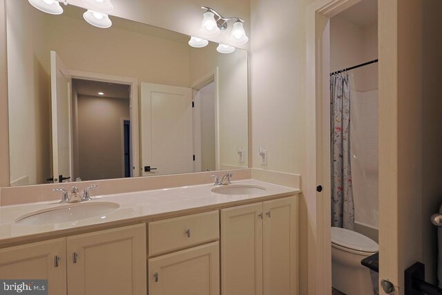 full bathroom featuring a sink, shower / bath combo with shower curtain, toilet, and double vanity