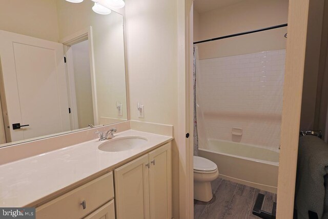 bathroom featuring vanity, shower / bath combo with shower curtain, toilet, and wood finished floors