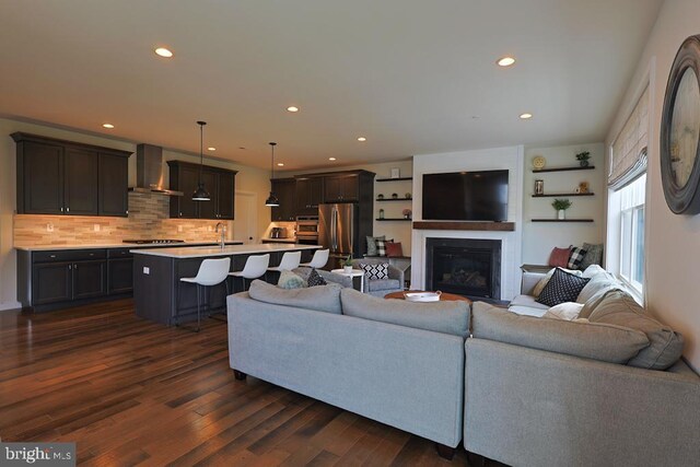 living area with a glass covered fireplace, recessed lighting, and dark wood-type flooring