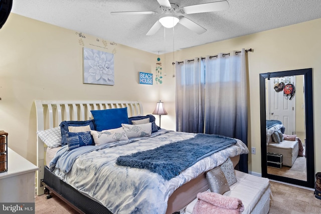 bedroom with a ceiling fan, a textured ceiling, and light carpet