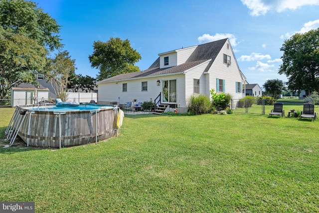 rear view of property with a lawn, a fenced backyard, a fenced in pool, and entry steps