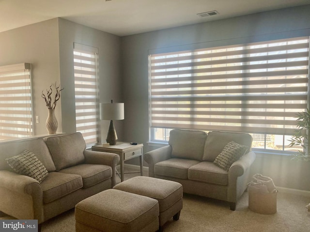 carpeted living area with baseboards, visible vents, and plenty of natural light